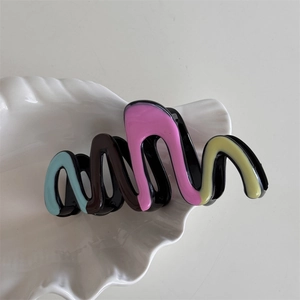 Detail of wave-shaped glossy resin hair claw with colorful blue and pink pattern