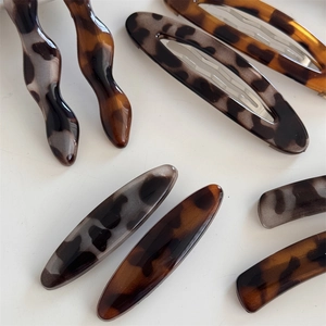 Elegant acetate leopard print hair clip and wave hairpin set on a white background