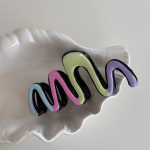 Macro detail of wave-shaped hair claw clip with colorful oil-painted marble texture