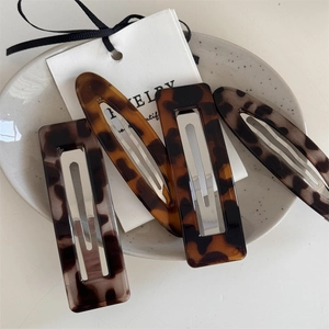 Detailed view of four retro acetate leopard print hair clips on a ceramic plate decor