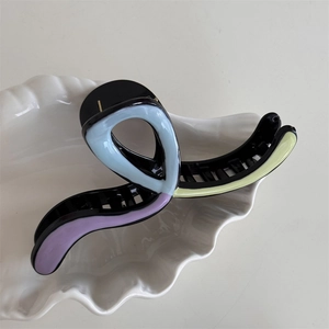 Detail of elegant wavy hair claw clip with morandi color mosaic design on white tray