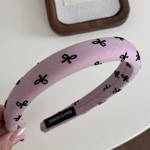 Détail du serre-tête fait main violet avec motifs de nœuds noirs et étiquette tissée