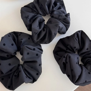 Detailed set of three black scrunchies with polka dots, bows, and heart patterns