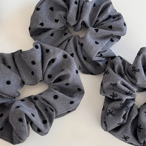 Detailed view of grey scrunchies with black heart, polka dot and bow patterns
