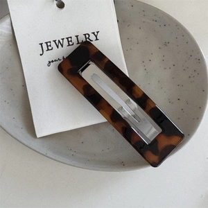 Detailed close-up of a rectangular tortoiseshell hair clip with a classic amber pattern