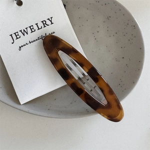 Macro shot of large oval leopard print hair clip on a minimalist display card