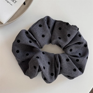 Detail shot of a grey polka dot scrunchie with soft twill fabric and flocked black dots