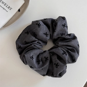 Detailed texture of dark grey polka dot bow scrunchie with woven fabric patterns