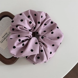 Détail d'un chouchou rose géant à pois noirs avec une texture de tissu plissé et doux