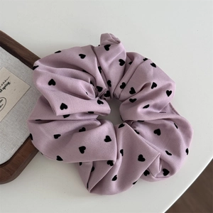 Détail macro du chouchou lavande avec motifs de cœurs noirs et plis en coton doux