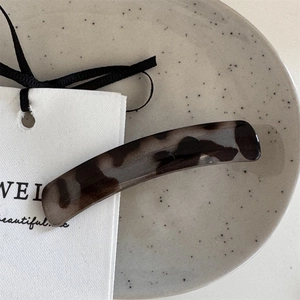 Macro detail of tortoiseshell acetate hair clip on an elegant minimalist display