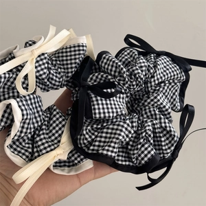 Détail de deux chouchous à carreaux avec nœuds en satin et perles en noir et blanc