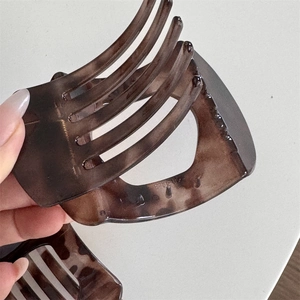 Detailed close-up of amber tortoiseshell hair claw showing non-slip teeth and grip