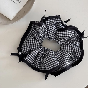 Détail du chouchou à carreaux avec un nœud en soie noire et des perles blanches