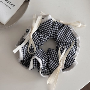 Détail d'un chouchou en tissu vichy noir et blanc avec nœud en ruban blanc et perle