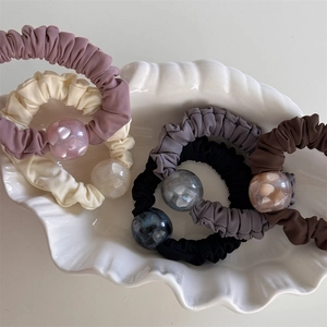 Eleganti elastici per capelli a pieghe con perle in resina su un piatto di porcellana