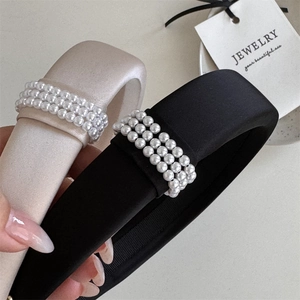 Close-up of elegant black and white padded headbands with triple-row pearl embellishments