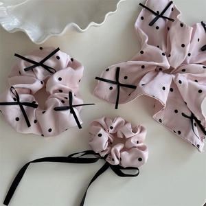 Dettaglio di tre elastici per capelli rosa a pois con elegante consistenza in raso di seta