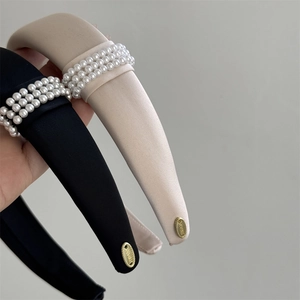 Elegant satin headband set with three rows of pearls and gold logo detail