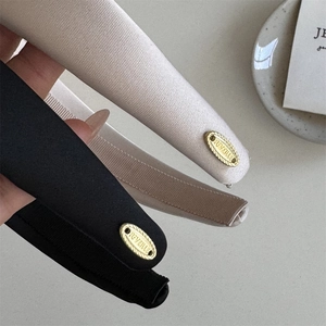 Detailed macro view of black and beige fabric headbands with elegant golden metal brand tags