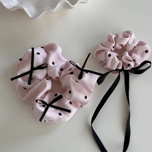 Dettaglio di due elastici scrunchie in raso rosa chiaro a pois con fiocchi di nastro