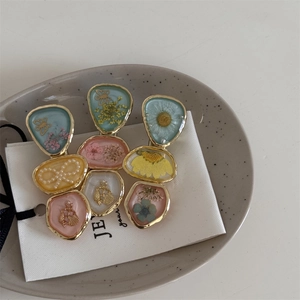 Detailed macro view of resin hair clips with dried flowers and pearl accents