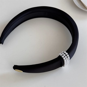 Detail of elegant black padded headband featuring white pearl beads and a gold accent piece