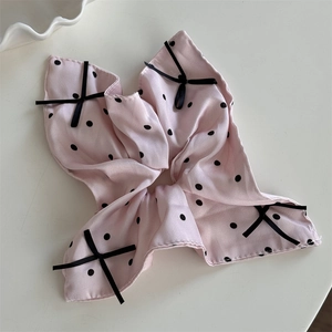 Dettaglio di un elastico rosa a pois con quattro eleganti fiocchi di nastro nero