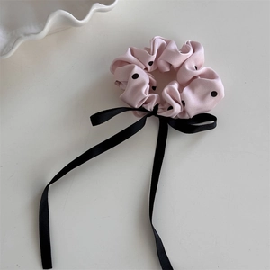 Dettaglio dell'elastico rosa a pois con un elegante fiocco lungo in nastro nero lucido