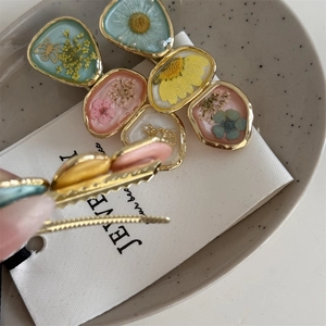 Detail view of colorful dried flower resin hair clip with gold metal duckbill base