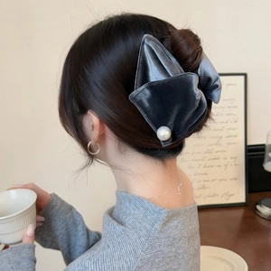 Detail of grey velvet bow hair claw with pearl accent worn on a French-style updo