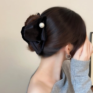 Close-up of elegant black velvet bow hair claw with pearl detail on a female hairstyle