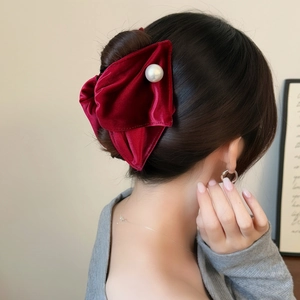 Elegant red velvet bow hair claw with pearl detail for women in a chic hair bun style