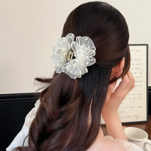 Detail of a large white organza flower hair claw clip with delicate lace and polka dots