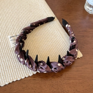 Détail d'un serre-tête marron à pois montrant les dents en plastique antidérapantes