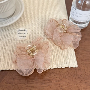 Detail of pink mesh flower hair claw clips with subtle polka dot embroidery on beige mat