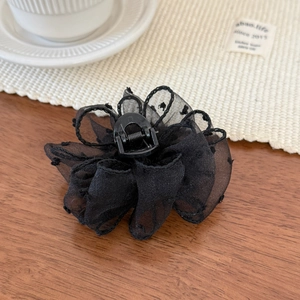 Detailed close-up of a black tulle flower hair claw clip with polka dot mesh texture