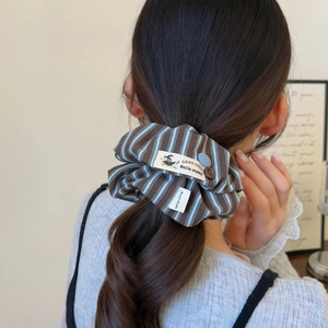 Chouchou rayé avec étiquette porte-bonheur et bouton décoratif sur les cheveux