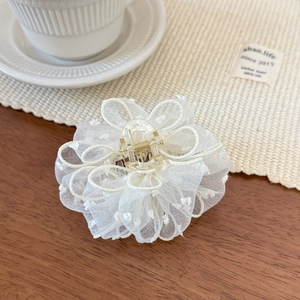 Detailed view of elegant white mesh flower hair claw with delicate polka dots on lace petals