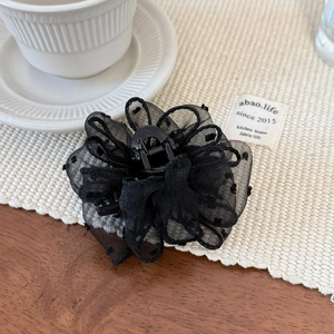 Detail shot of black lace flower hair claw clip with delicate polka dot embroidery texture