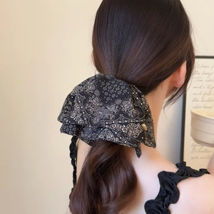 Detail of paisley print bow hair scrunchie styled in an elegant low ponytail