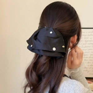 Elegant black polka dot satin bow hair claw clip with golden button on female hair