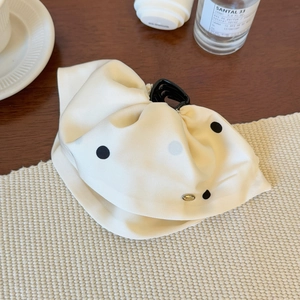 Detail of elegant cream polka dot satin hair claw clip with golden logo emblem