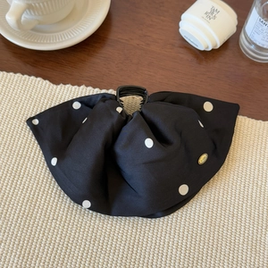 Detailed view of elegant black polka dot satin bow hair claw clip with golden metal tag