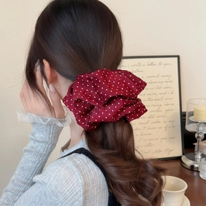 Chouchou élégant rouge à pois blancs présenté sur une queue de cheval dans un décor chic
