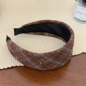 Detail view of brown plaid linen headband with gold metal tag and non-slip lining