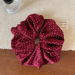 Chouchou élégant rouge bordeaux à pois avec tissu plissé sur un support tressé