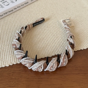 Detail view of brown tweed fabric headband with white pearls and internal hair comb teeth