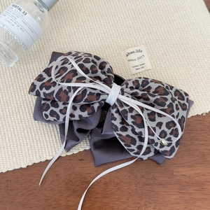 Close-up of leopard print bow hair claw with satin layers and white ribbon detail