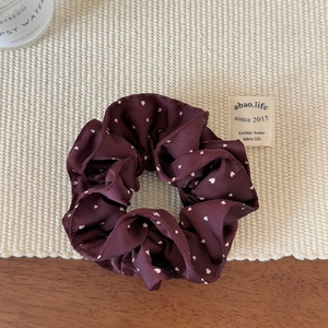 Dettaglio dell'elastico scrunchie bordeaux a doppio strato con cuori su base intrecciata